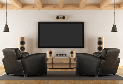 Heimkinozimmer mit zwei schwarzen Ledersesseln, großem Fernseher und Surround-Sound-System in Holzoptik.