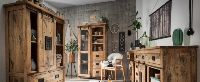 Rustikales Wohnzimmer mit massiven Holzmöbeln, Betonwand und dekorativen Pflanzen.
