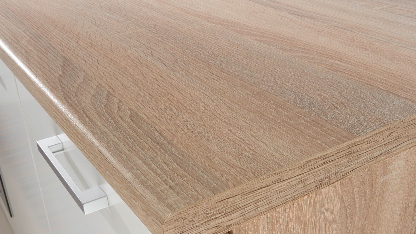 Nahaufnahme einer Küchenarbeitsplatte in Holzoptik mit sichtbarer Maserung und abgerundeter Kante, darunter ein weißer Unterschrank mit Metallgriff.