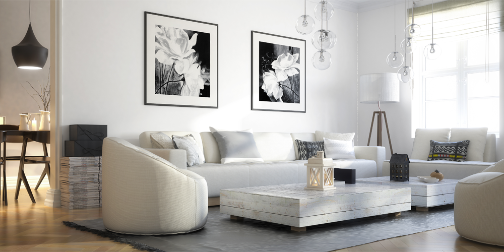Modernes Wohnzimmer mit heller Couchgarnitur, flachem Couchtisch aus Holz, schwarzen Dekokissen und zwei Blumenbildern an der Wand.