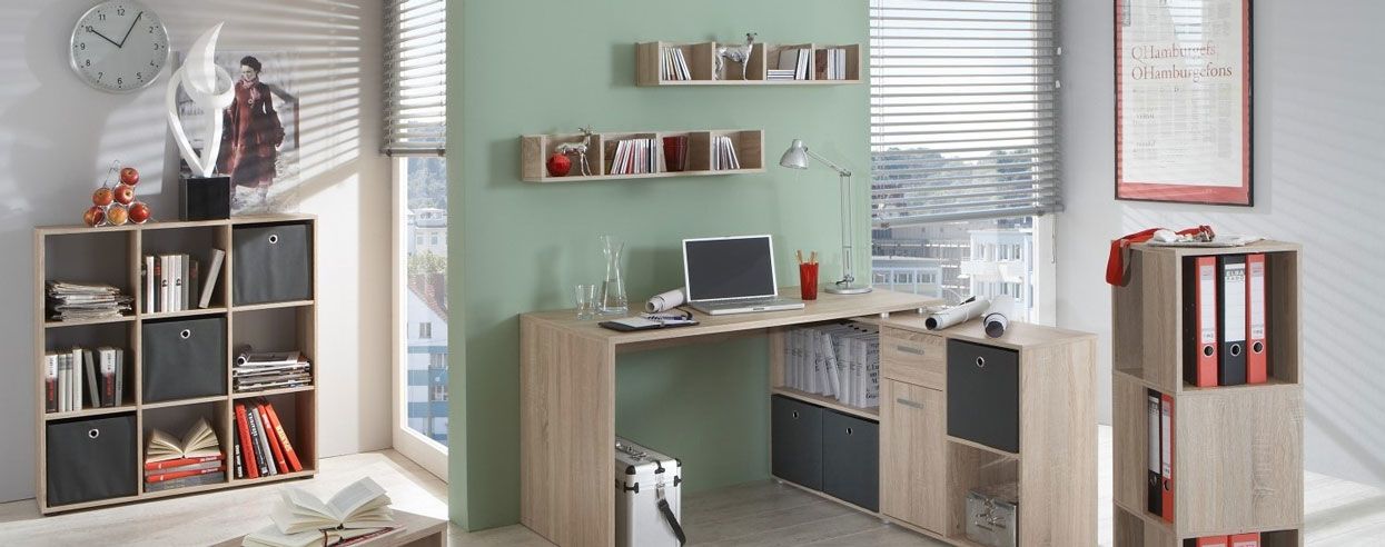 Modernes, helles Arbeitszimmer mit L-förmigem Schreibtisch aus Holzoptik, Regalwürfeln, Laptop und vielen Ordnern sowie Deko-Elementen.